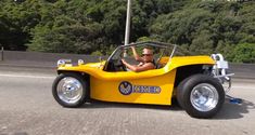 a man driving a yellow car down the road