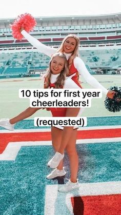 two cheerleaders standing on the sidelines at a football stadium