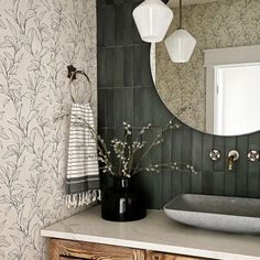 a bathroom with a sink, mirror and wallpapered walls in black and white