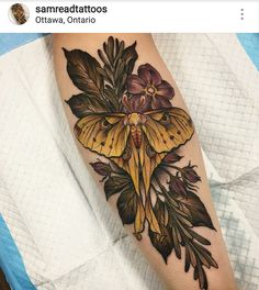 a yellow moth with leaves and flowers on the arm