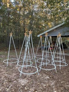 four white metal stands with gold stars on them in front of a shed and trees