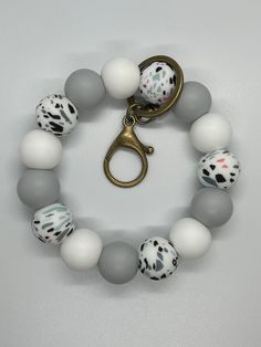 a bracelet with white and gray beads, gold tone metal clasp and an animal print bead