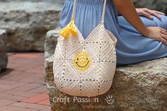 a woman sitting on a rock with a crocheted bag