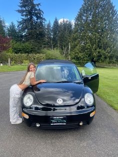 a woman leaning on the hood of a black car