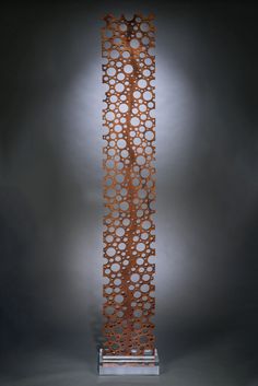 a tall metal sculpture with circles on it's sides and a light in the background