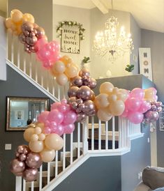 the staircase is decorated with balloons and streamers in pink, gold and silver colors