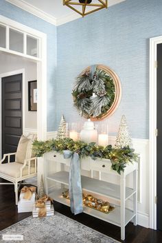 a decorated console table with candles and greenery