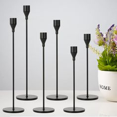 four black candles stand next to a potted plant