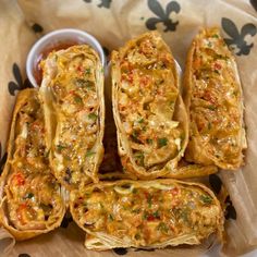 some food is laying out on a paper wrapper next to a bowl with dipping sauce