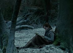 a woman sitting in the woods reading a book