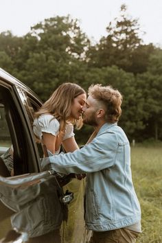 a man kissing a woman's face while leaning on the door of a car