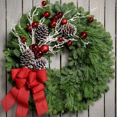 Christmas wreath made with noble fir, pine, pine cones, snow-covered branches, red balls and a red burlap bow close up Dekoratívne Vence, Fresh Wreath, Burlap Christmas Tree, Pine Wreath, Burlap Christmas, Red Ornaments, Xmas Wreaths, Handmade Christmas Decorations, Noel Christmas