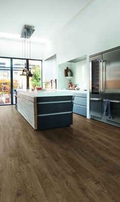 a kitchen with wood flooring and stainless steel refrigerator freezer next to an island