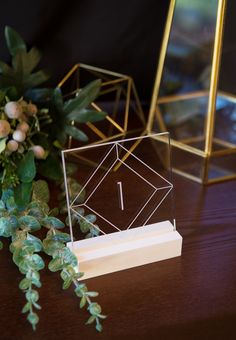 the table is set up with two gold and white geometric boxes, greenery and flowers