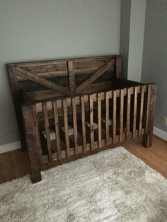 a wooden bed frame sitting on top of a white rug in front of a gray wall