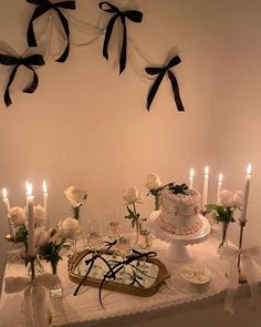 a table topped with a cake covered in frosting next to white roses and candles