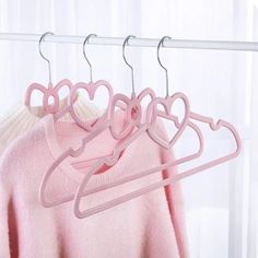 three pink heart shaped clothes hangers on a white rail