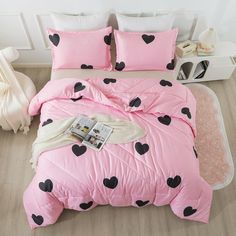 a pink bed with black hearts on it and a magazine laying on the comforter