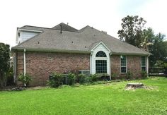 a brick house sitting in the middle of a lush green yard