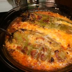 a casserole dish with green peppers and cheese in it on top of a stove