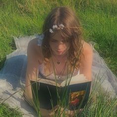 a girl reading a book in the grass