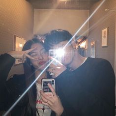 a man and woman taking a selfie in front of a mirror