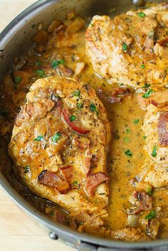 two pieces of chicken in a pan with tomatoes and herbs