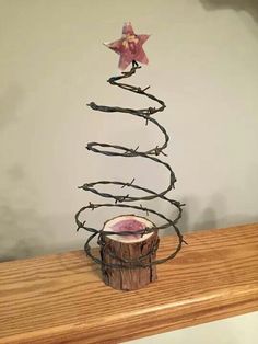 a wire christmas tree on top of a wooden table next to a star ornament