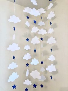 a crib mobile with stars and clouds hanging from it's sides on a wall