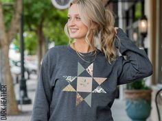 a woman is smiling while wearing a sweater with an origami design on it