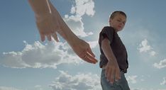 a young boy holding the hand of an adult's hand in front of blue sky