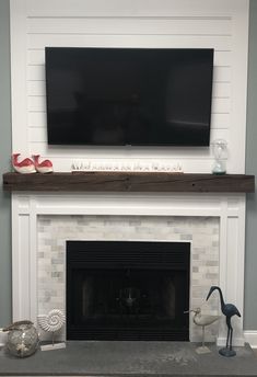 a fireplace with a flat screen tv above it and other decorations on the mantel