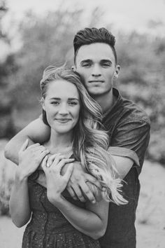 a man and woman hugging each other in black and white