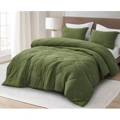 a bed with green comforter and pillows