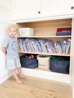 a little boy standing in front of a cabinet filled with items