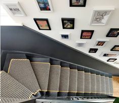 the stairs are lined with black and white striped rugs, framed pictures on the wall above them