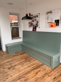 a green bench sitting on top of a wooden floor next to a wall with pictures above it