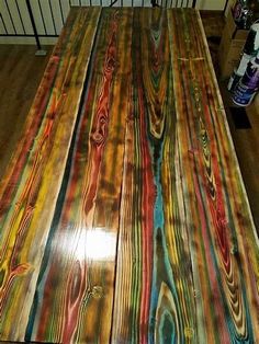 the table is made out of wood and has multicolored paint on it's surface