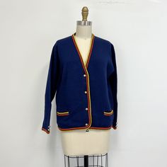 "Vintage lambswool cardigan sweater featuring; a deep v neck long sleeves with w gold buttons at the cuff inset pockets at the hips buttons down the front with gold metal buttons Of a smooth, mid weight, 100% lambswool knit in navy blue the openings and pockets are trimmed in yellow and orange. Labeled \"Saks Fifth Avenue, Full Fashioned Lambrosia, 100% Lambswool\"  with no size tag, measurements when laid out flat are; 22 inches from pit to pit 20 1/2 inch sleeve 18 inches across the bottom 14 Retro Long Sleeve Cardigan For Work, Long Sleeve V-neck Sweater For Work With Buttons, Blue Retro Long Sleeve Cardigan, Blue Vintage Sweater With Button Closure, Vintage Navy Long-sleeve Outerwear, Vintage Blue V-neck Outerwear, Vintage Blue V-neck Cardigan, Vintage Suede, Patchwork Skirt