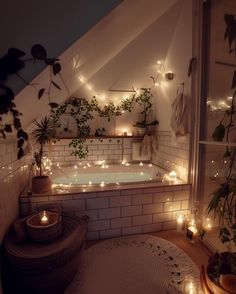 a bathroom with plants and candles on the walls, lights in the bathtub and potted plants