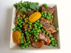 a white plate topped with meat and peas