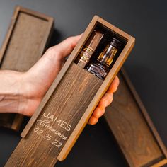 a person holding an open wooden box with three bottles in it