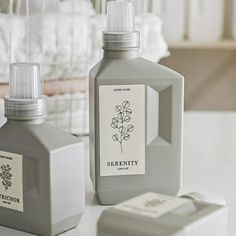 two bottles of soap sitting next to each other on a white counter top, one with a flower in it