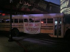 a bus with a banner on it sitting in front of a building