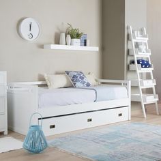 a bedroom with white furniture and a blue rug