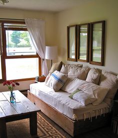 a living room with a couch, coffee table and two mirrors on the wall above it