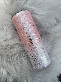 a pink glitter tumbler sitting on top of a fluffy white blanket