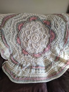 a white crocheted blanket sitting on top of a couch