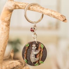 a keychain with a sloth hanging from it's side on a tree branch