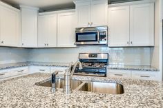 a kitchen with granite counter tops and white cabinets